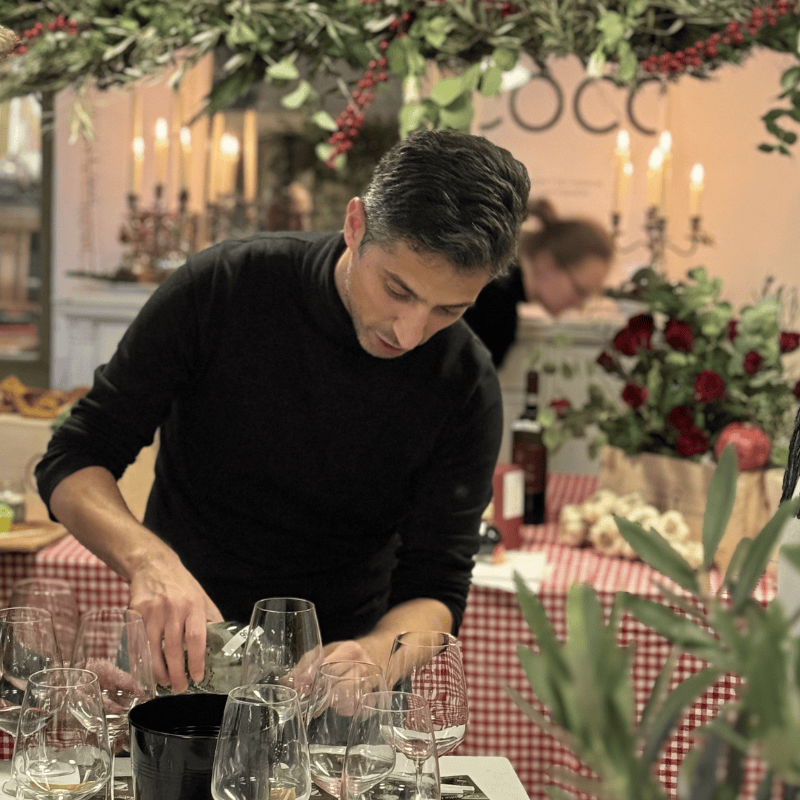 Ein Sommelier schenkt an der Weihnachtsdegustation vom 28.11.2026 Wein ein, umgeben von festlicher Dekoration und Weingläsern.
